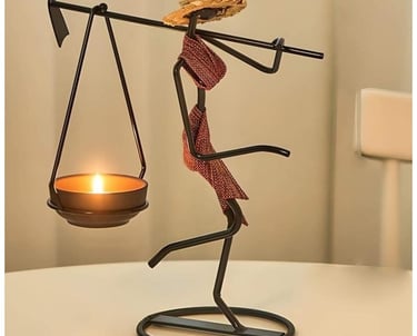 Wrought iron tea light candle holder shaped like a person with a hat and scarf.